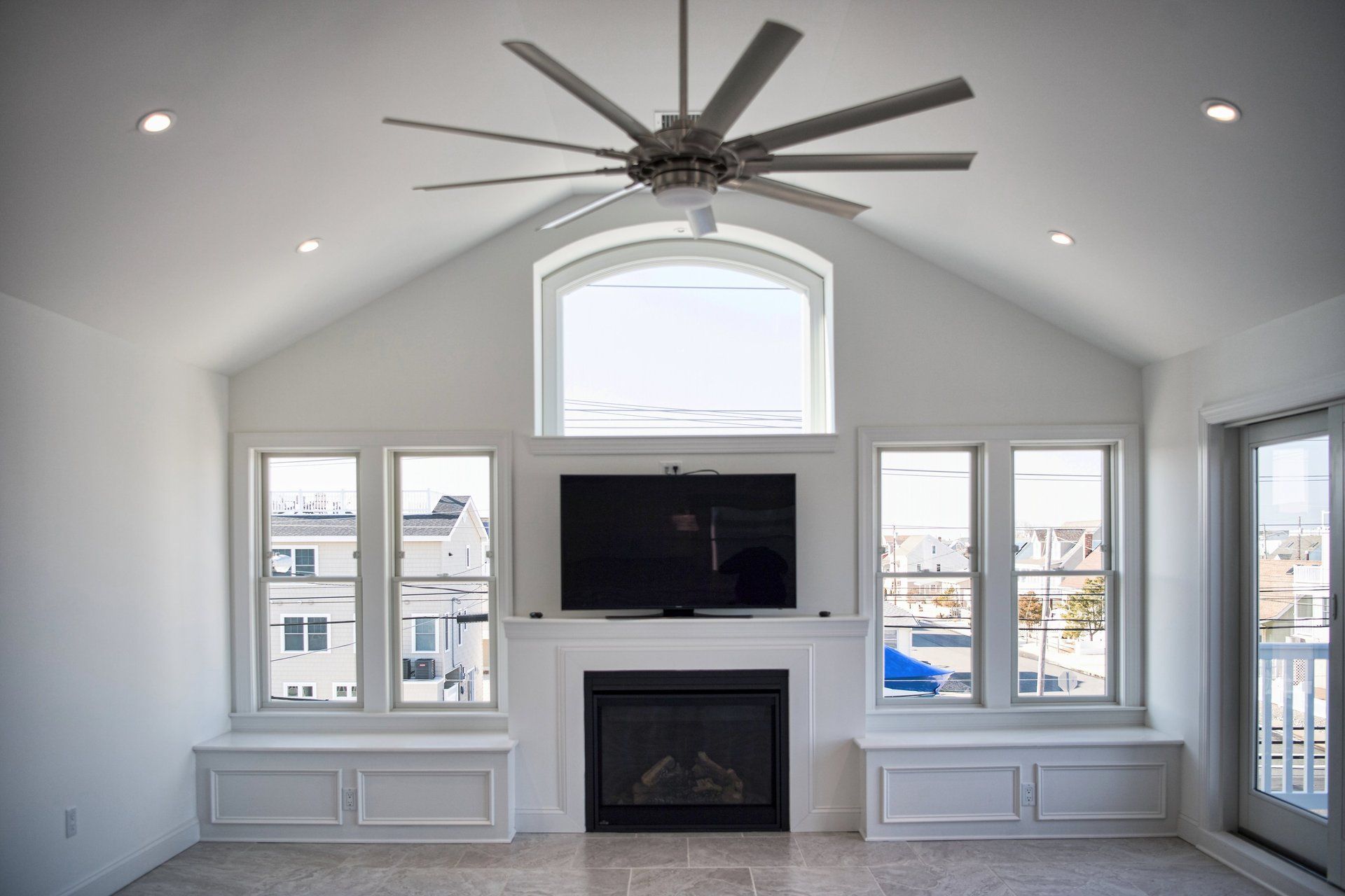 A living room with a fireplace , television , and ceiling fan.