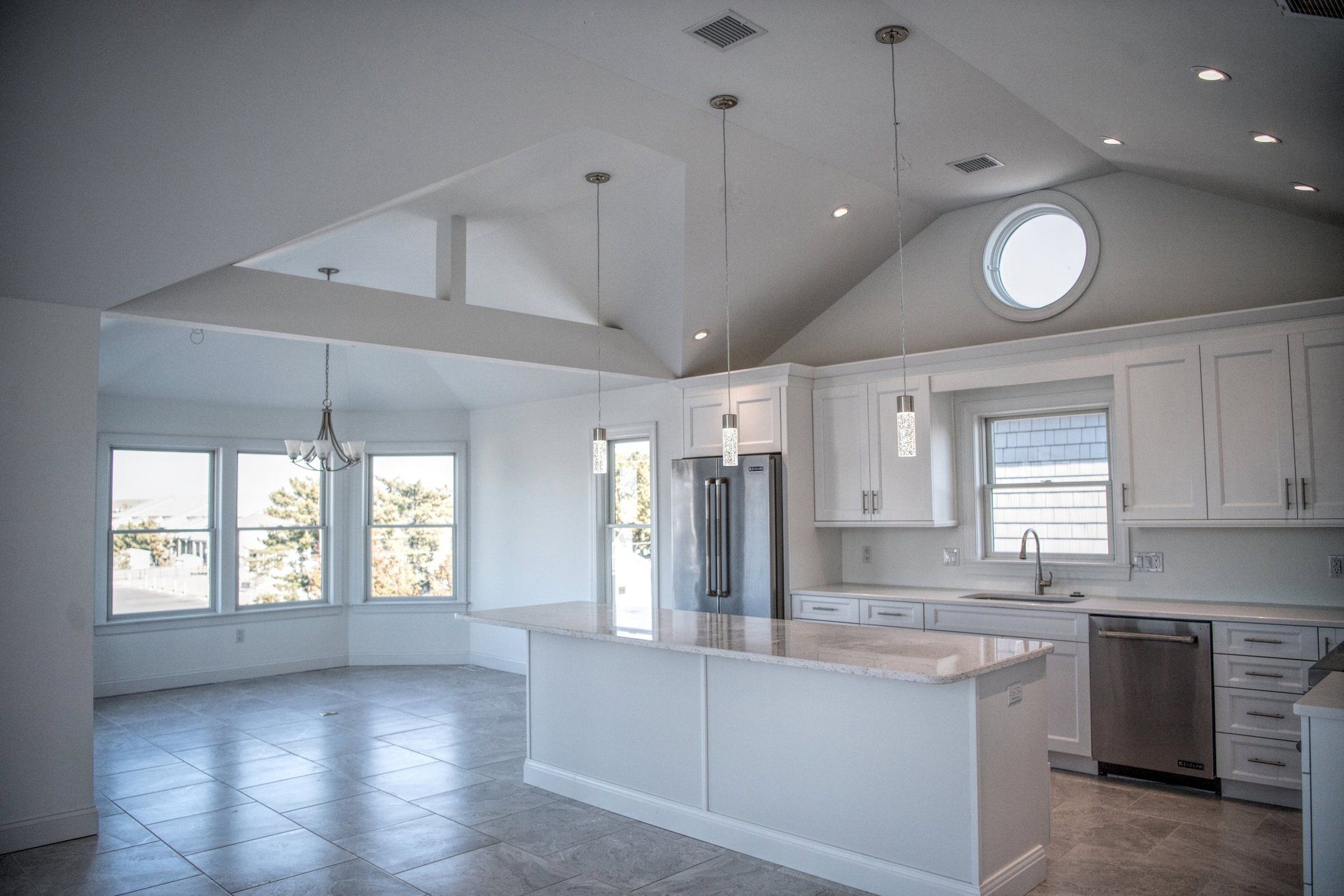 An empty kitchen with white cabinets and a large island.