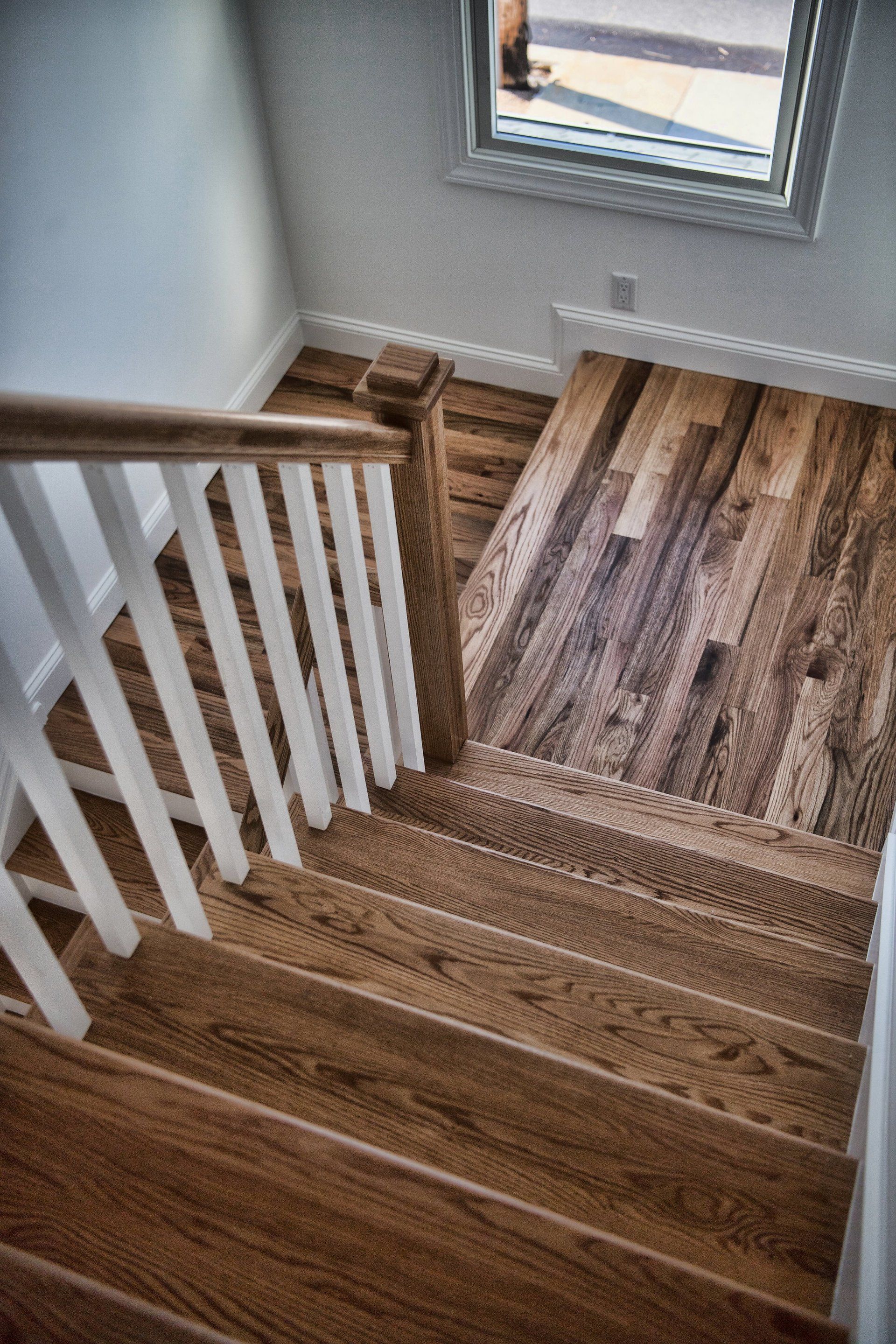 A wooden staircase with a white railing and a window.