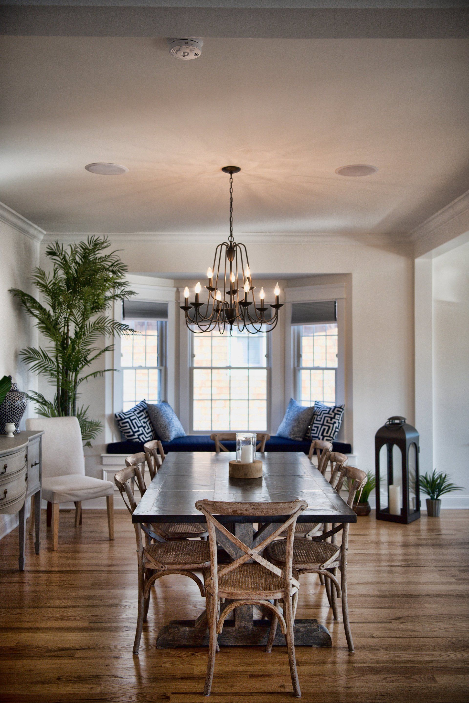 A dining room with a long table and chairs and a chandelier.