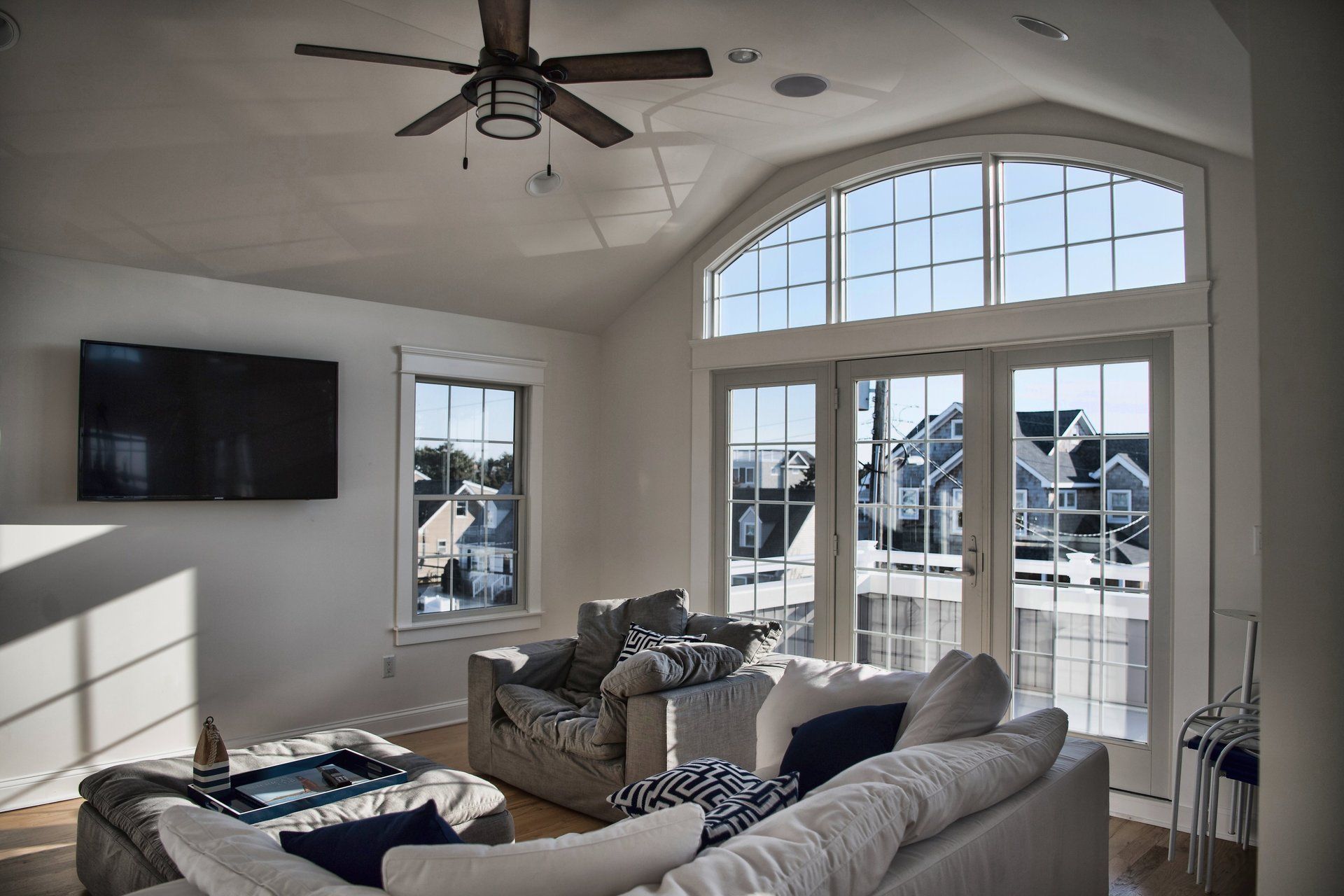 A living room with a ceiling fan and a flat screen tv.