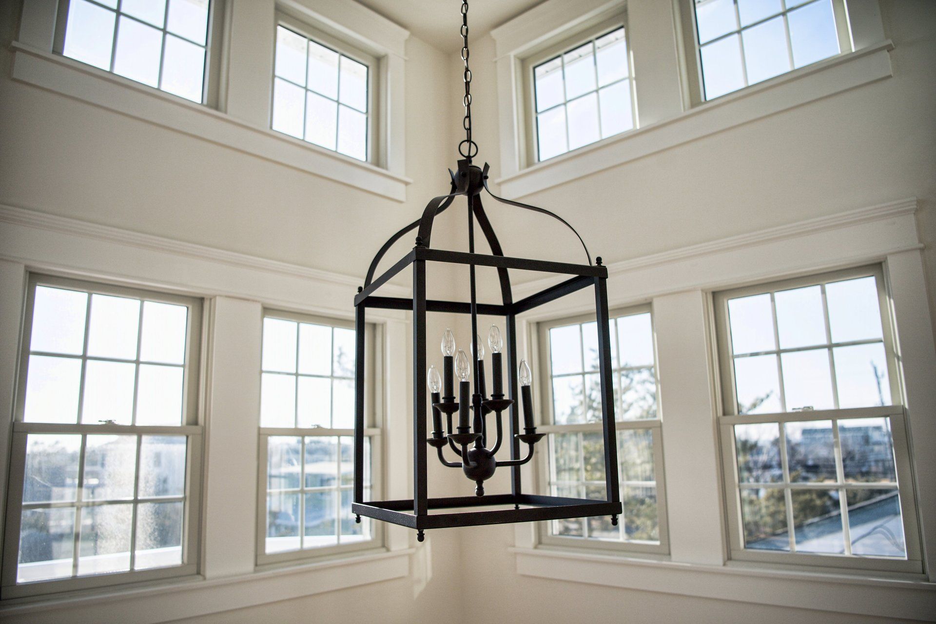 A chandelier is hanging from the ceiling in a room with lots of windows.