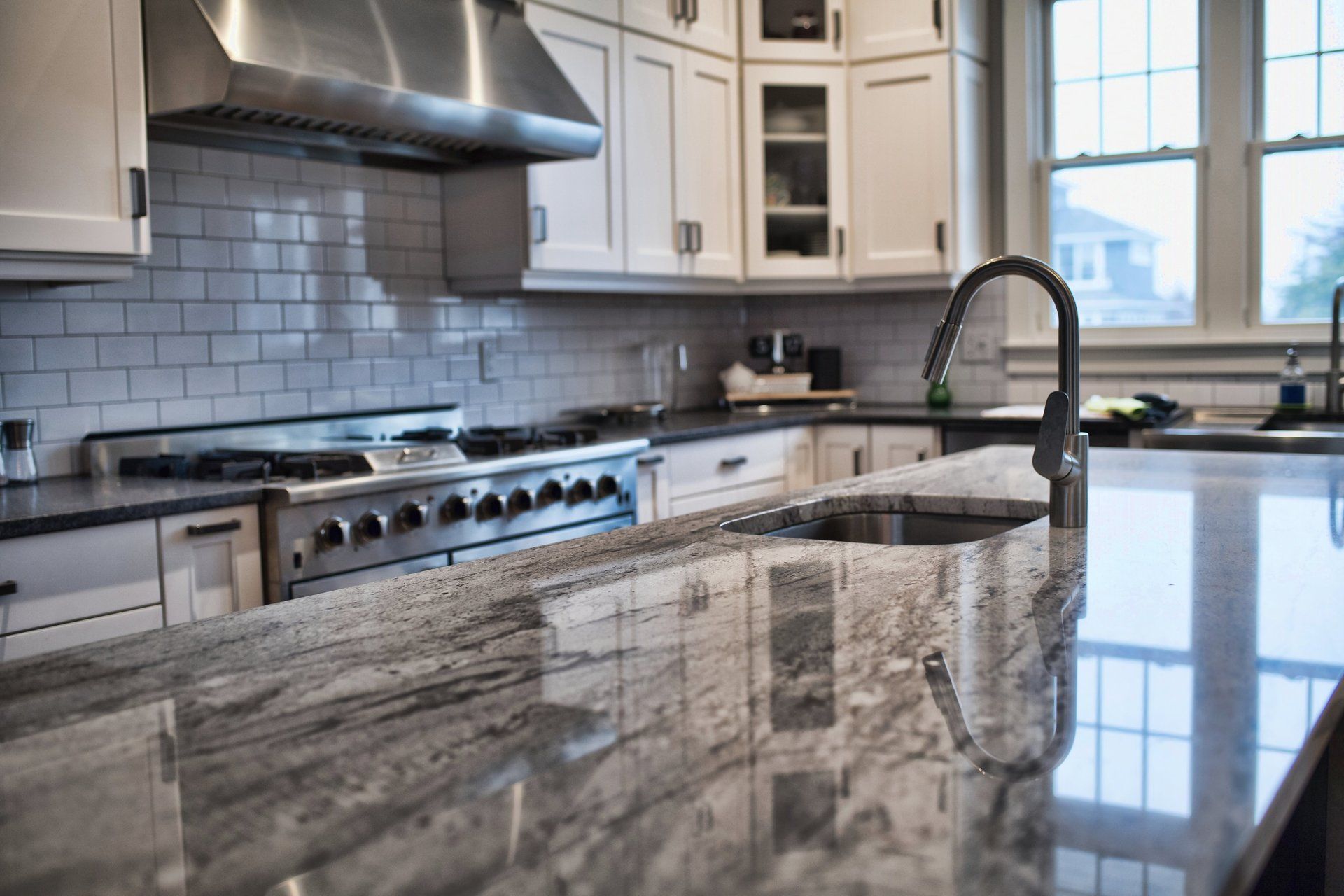 A kitchen with granite counter tops , stainless steel appliances , and white cabinets.
