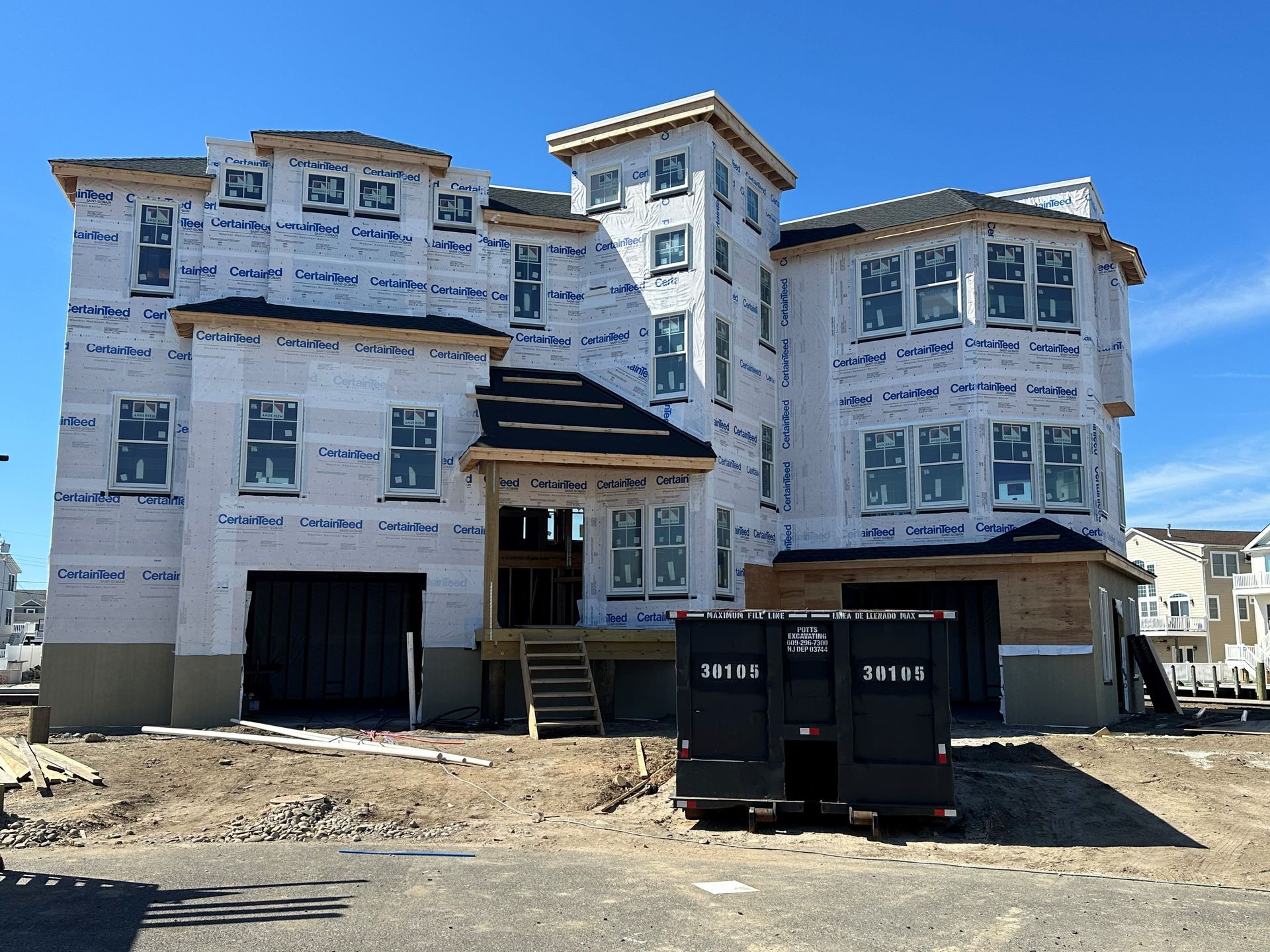 A large house under construction with a dumpster in front of it