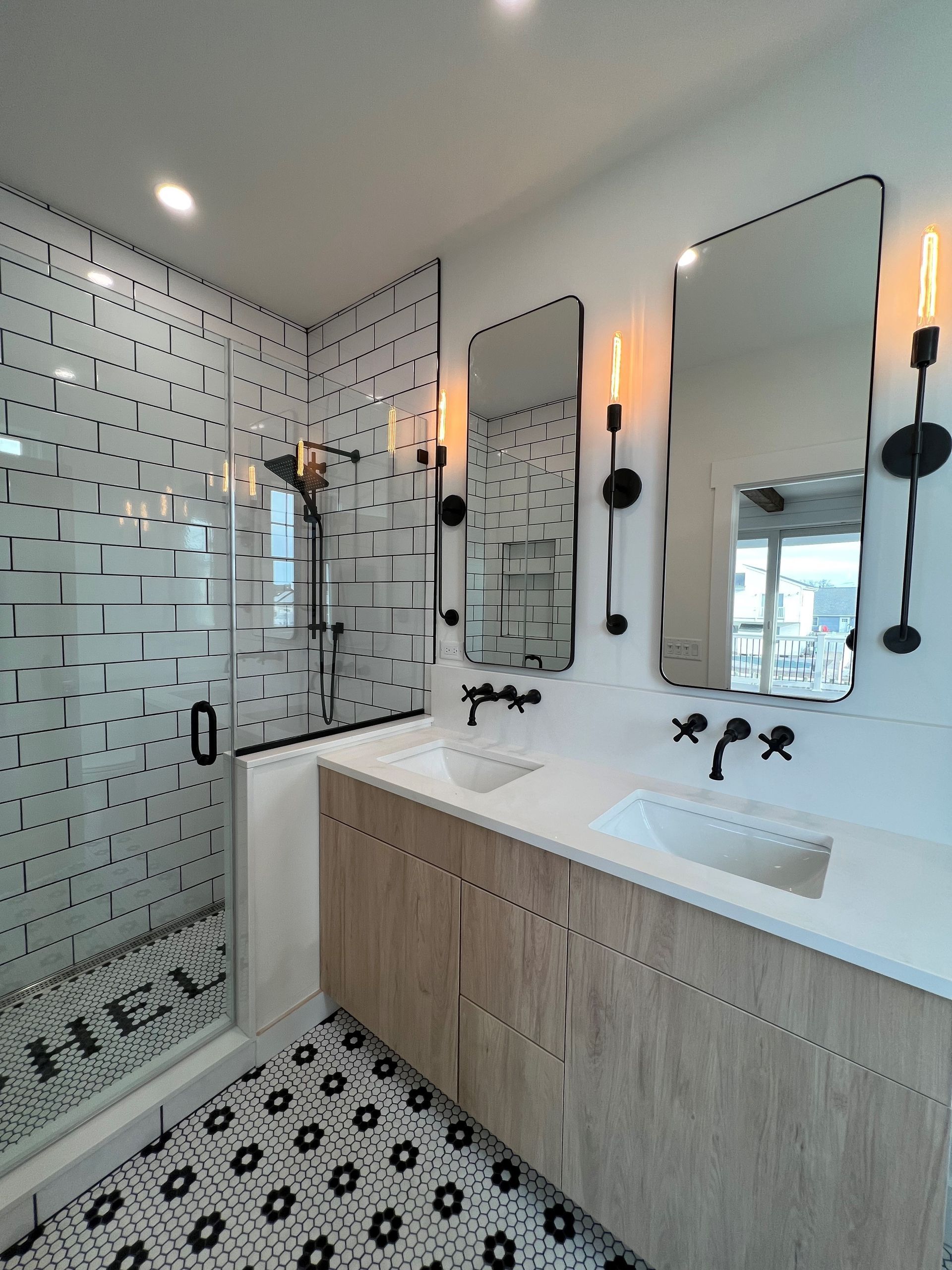 A bathroom with two sinks , two mirrors and a walk in shower.