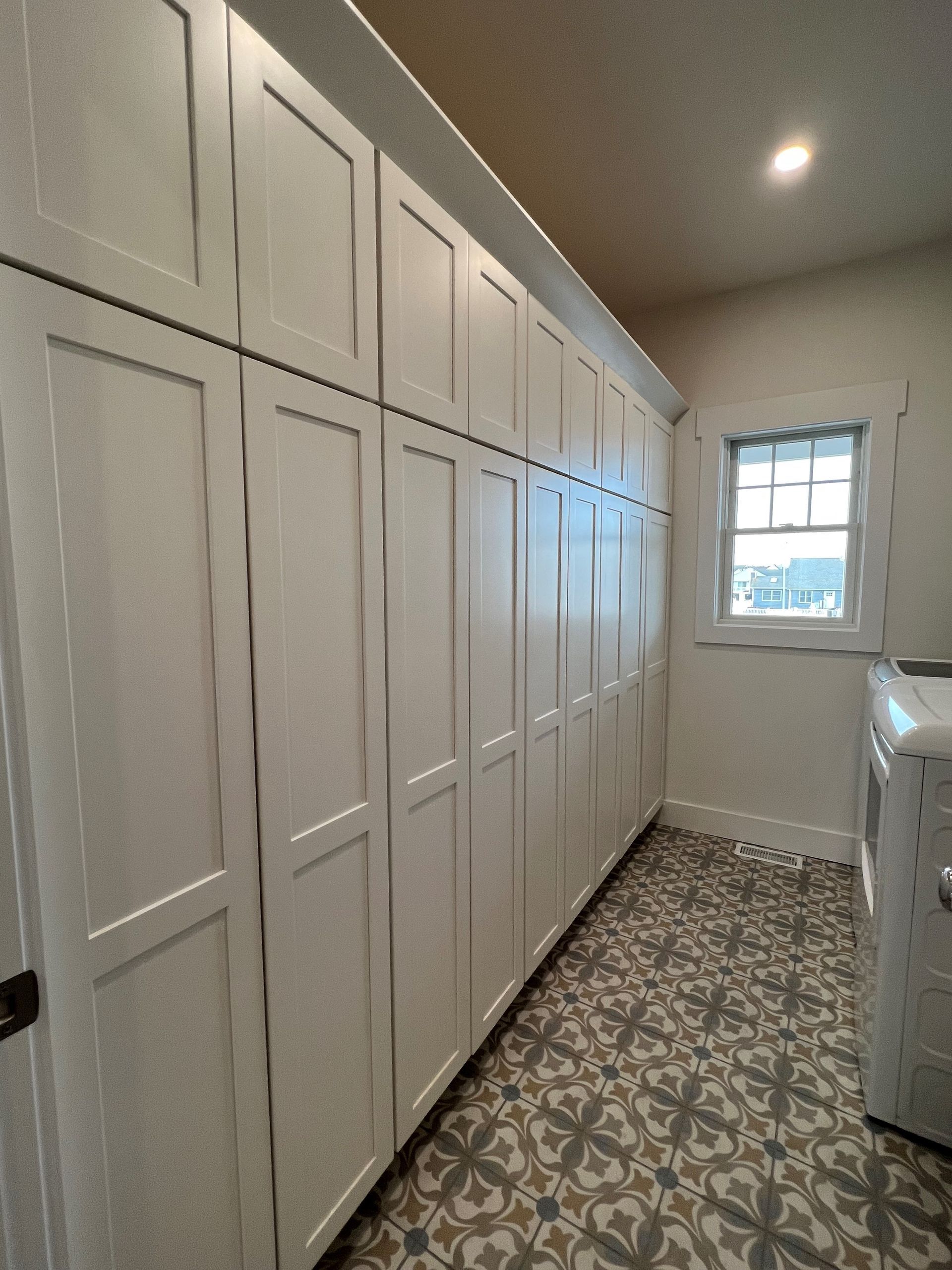 A laundry room with white cabinets , a washer and dryer , and a window.
