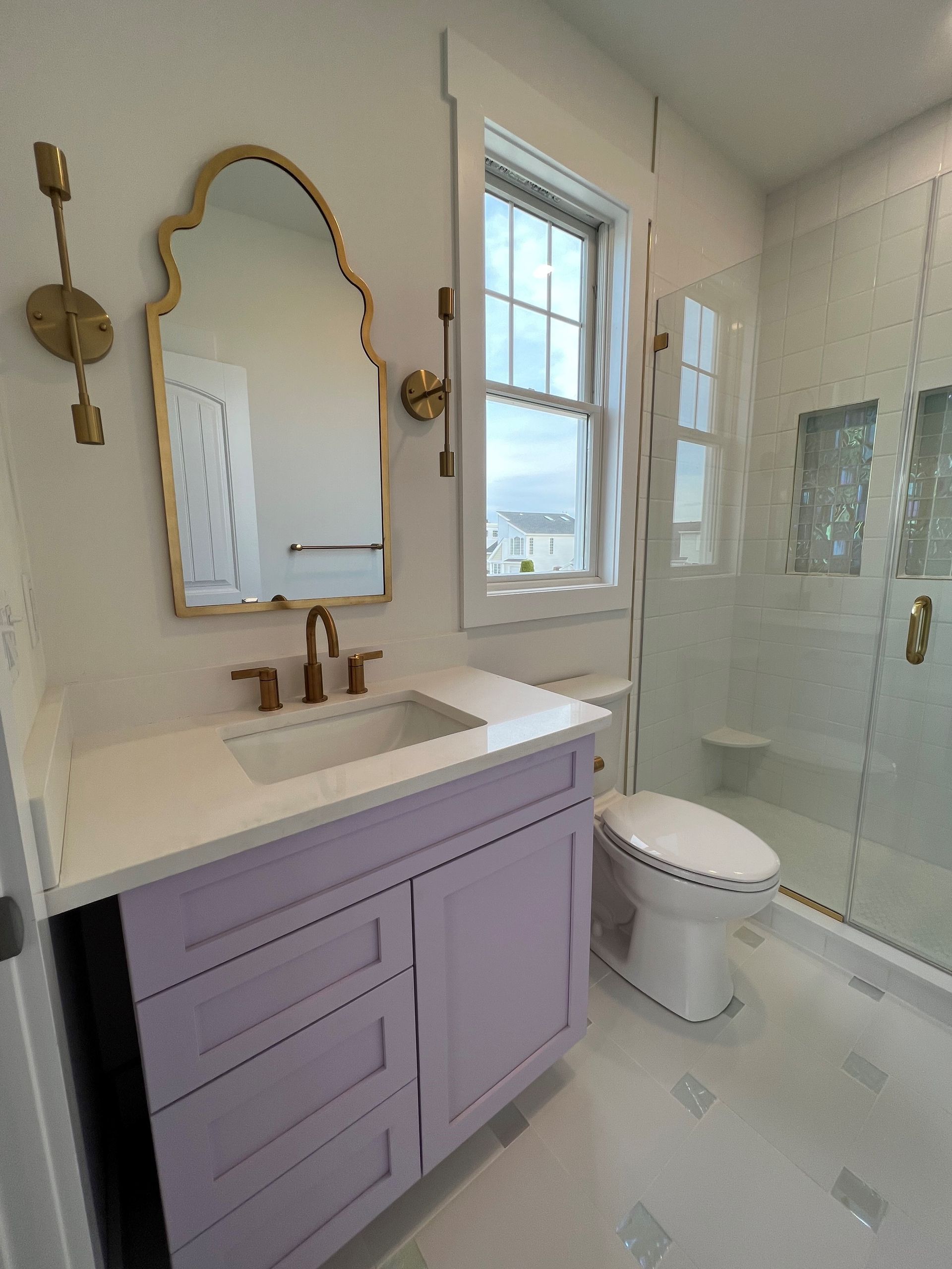 A bathroom with purple cabinets a toilet a sink and a mirror
