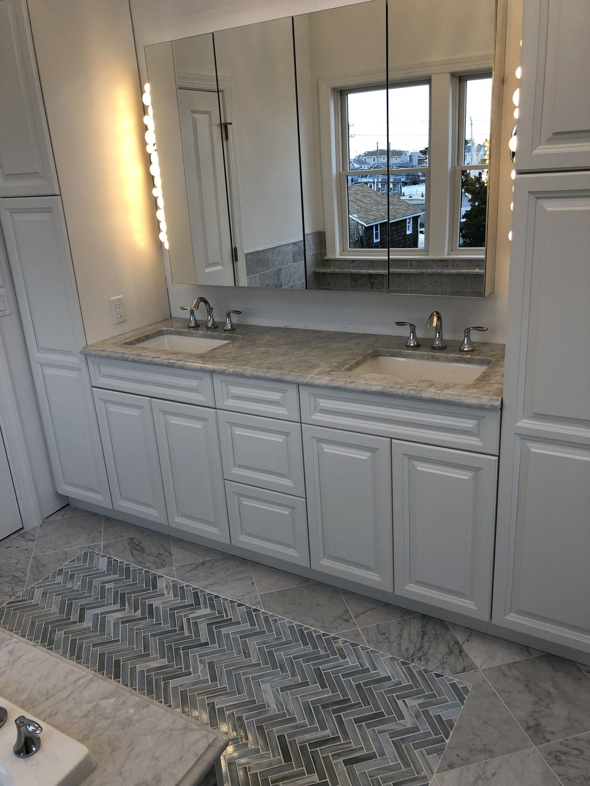 A bathroom with two sinks , a mirror and a window.