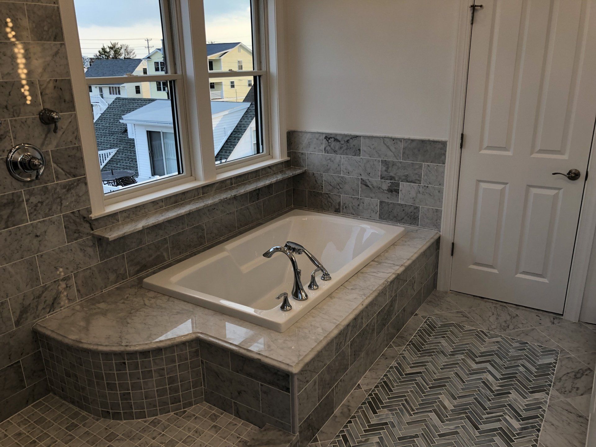 A bathtub in a bathroom next to a window.