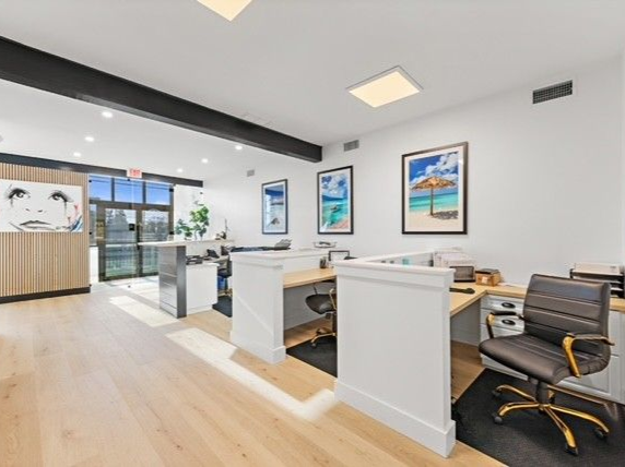 Bright office space with desks, artwork, and a view of the outdoors. 