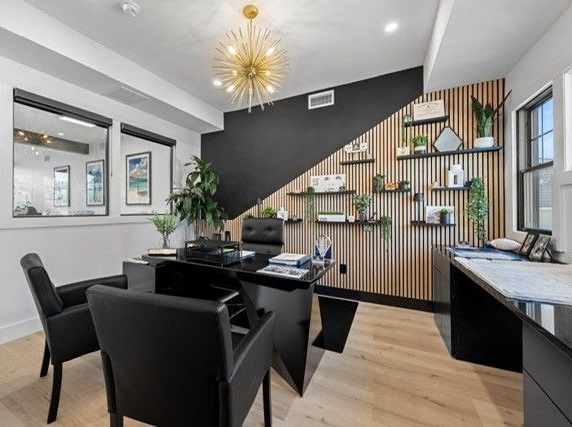 Office with a black desk, chairs, and accent wall with shelves. 