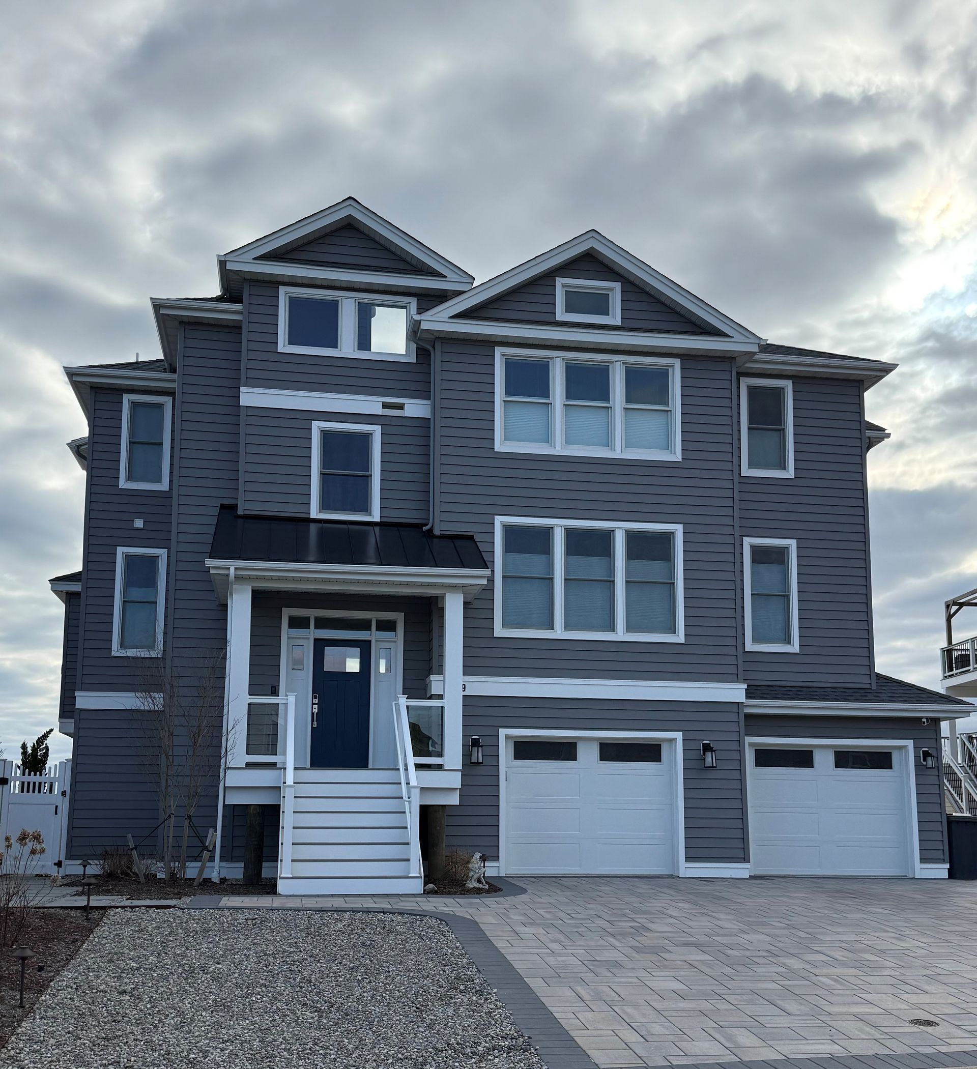 A large grey house with white trim and a blue door