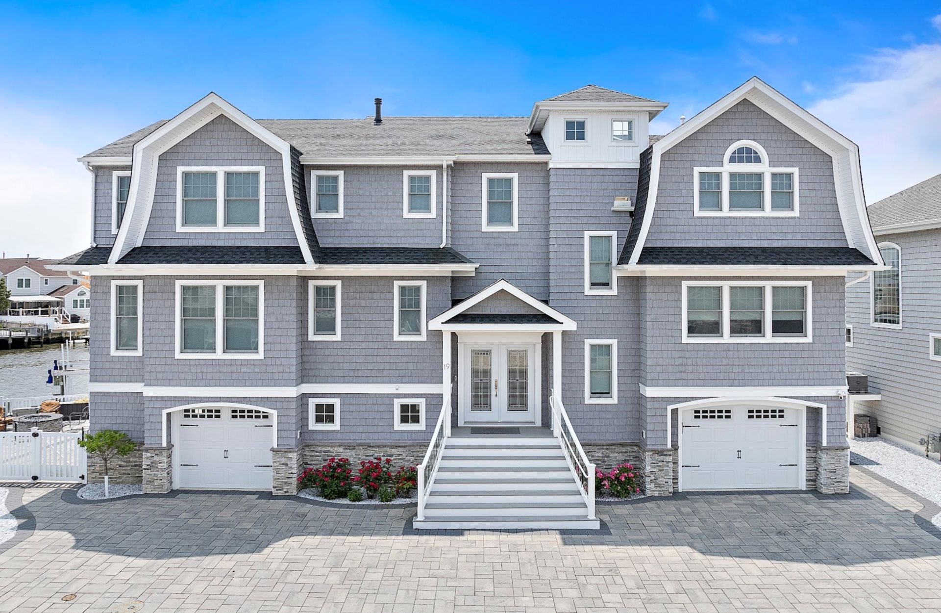 Gray multi-story house with white trim, two-car garage, and white stairs leading to the front doors.
