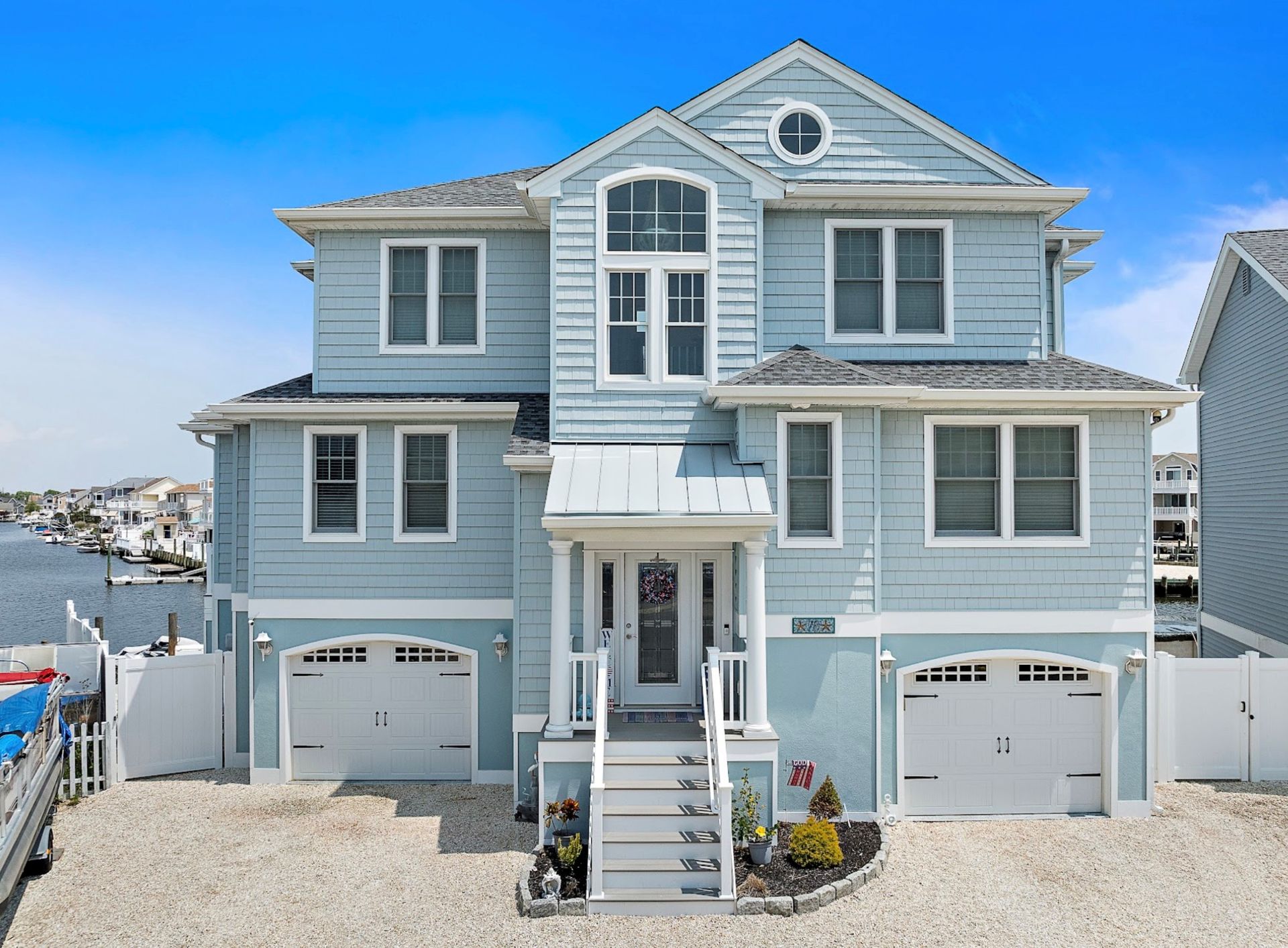 Blue house with white trim and two-car garage, steps leading to the front door.