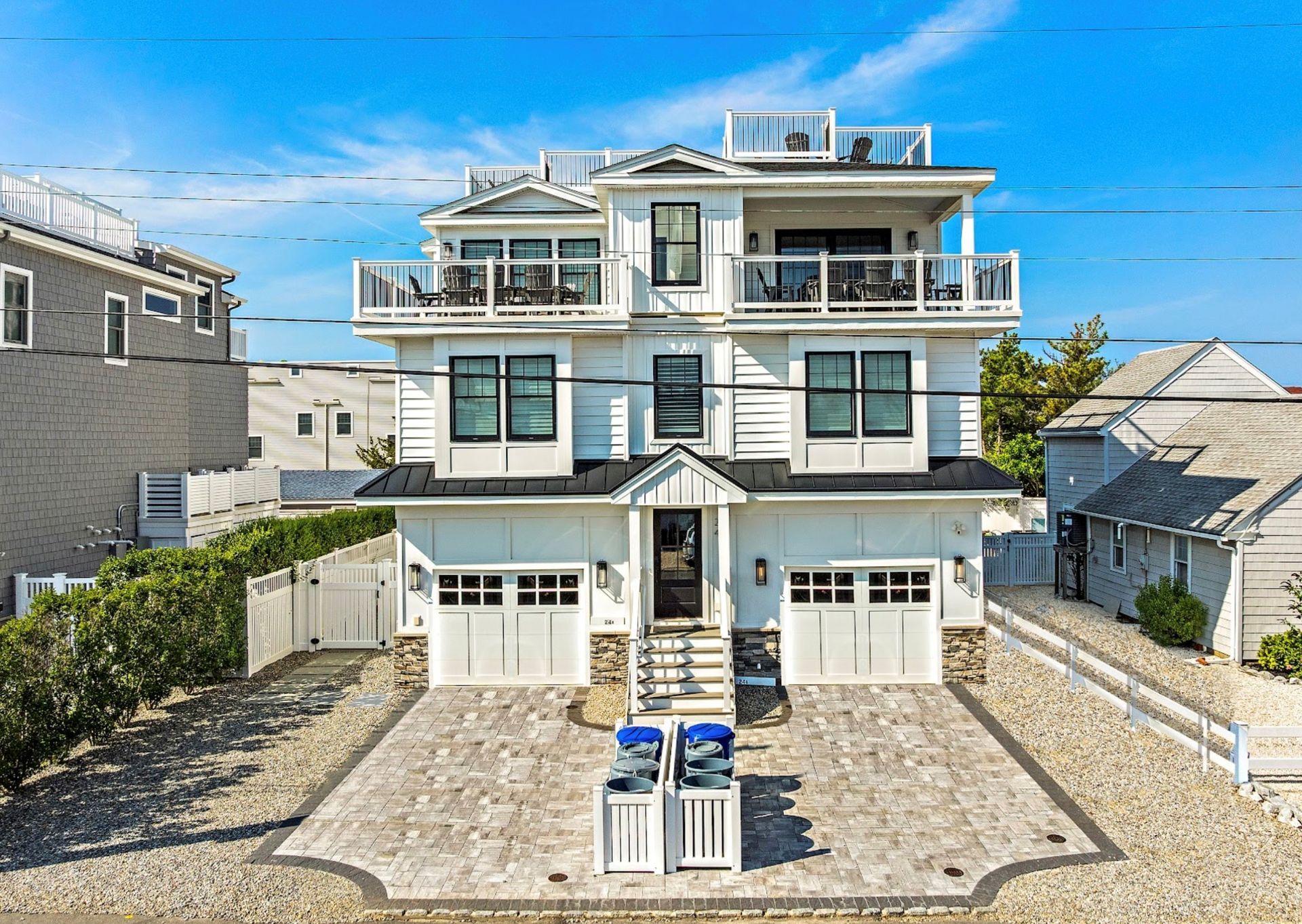 White multi-story house with balconies, garage, and blue sky.