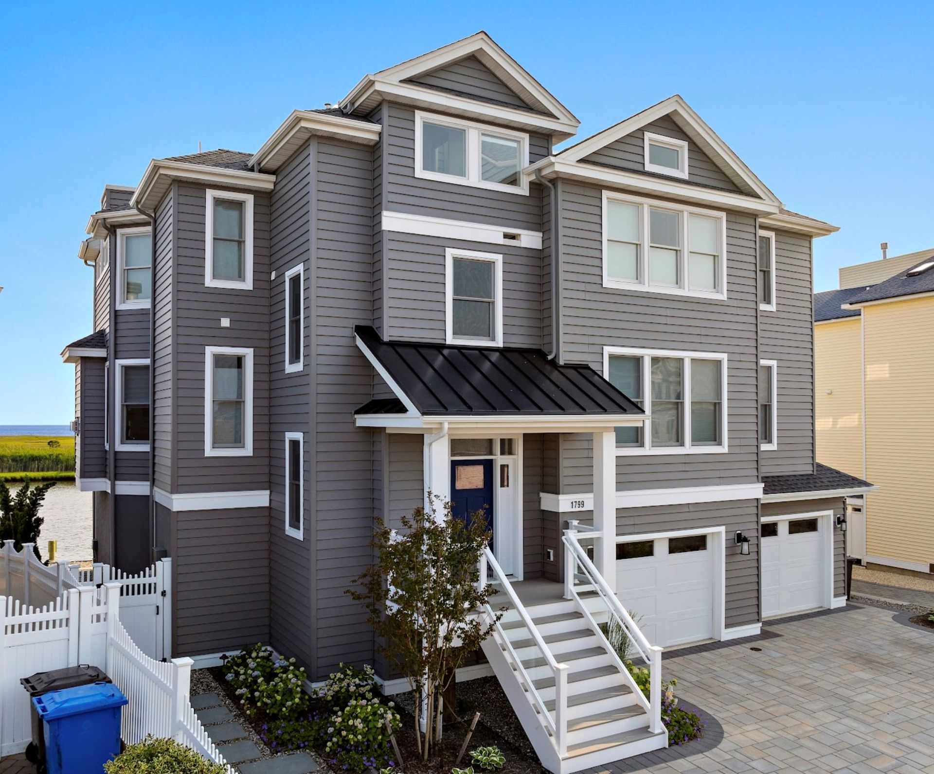 Gray multi-story house with white trim, a blue front door, and a two-car garage.