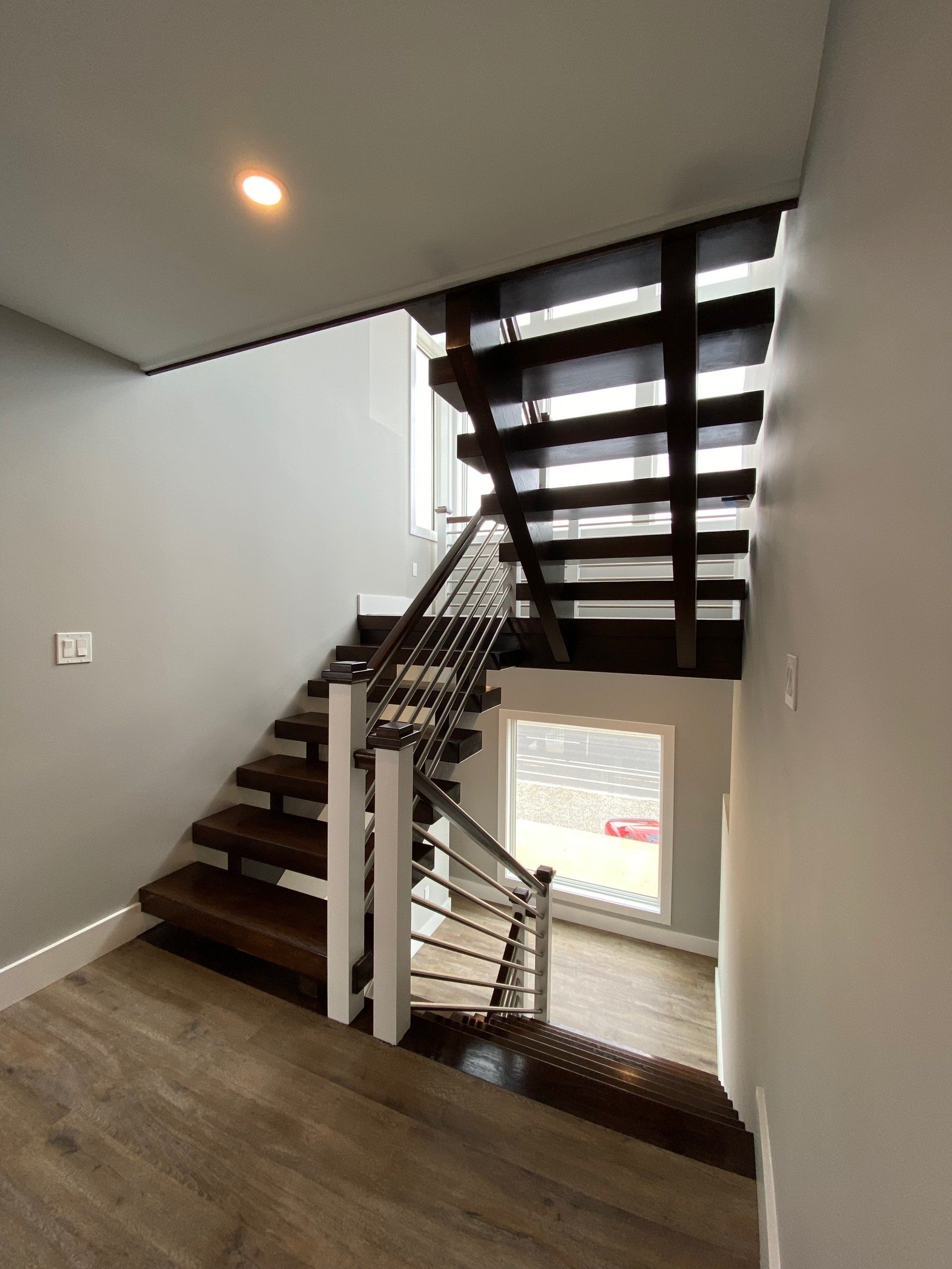 A staircase in a house with wooden steps and a metal railing.