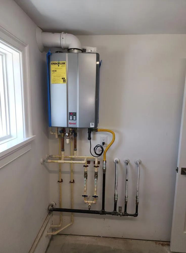 A wall-mounted Rinnai tankless water heater with plumbing connections and a yellow gas line in a utility room.