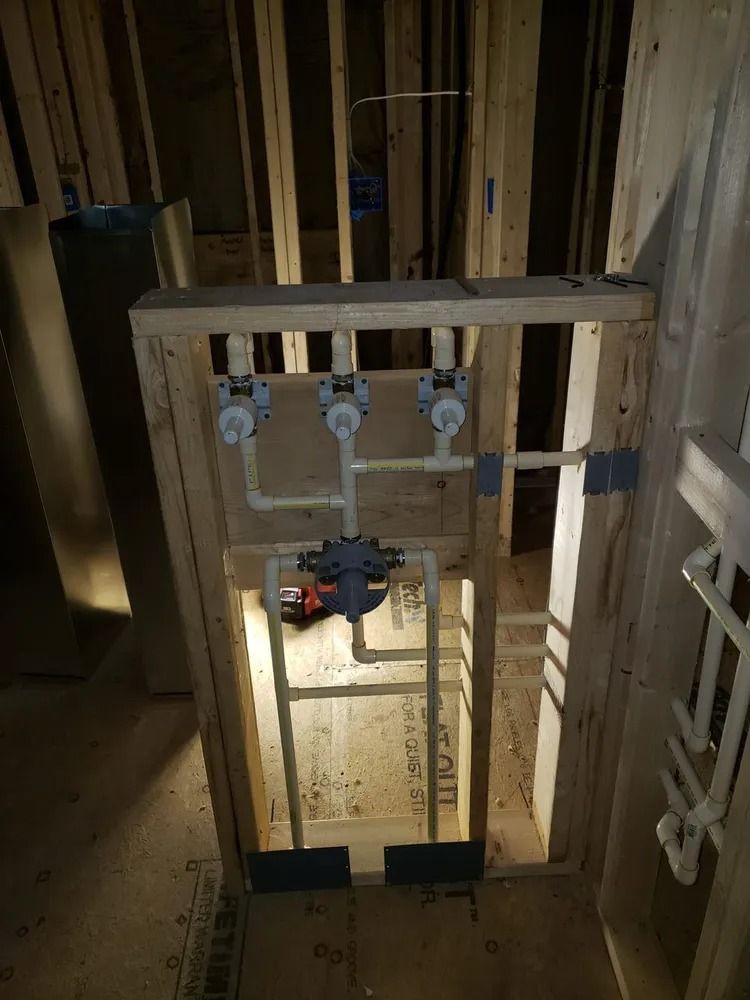 Rough-in plumbing for a shower system featuring a central mixing valve connected to three individual flow control valves.