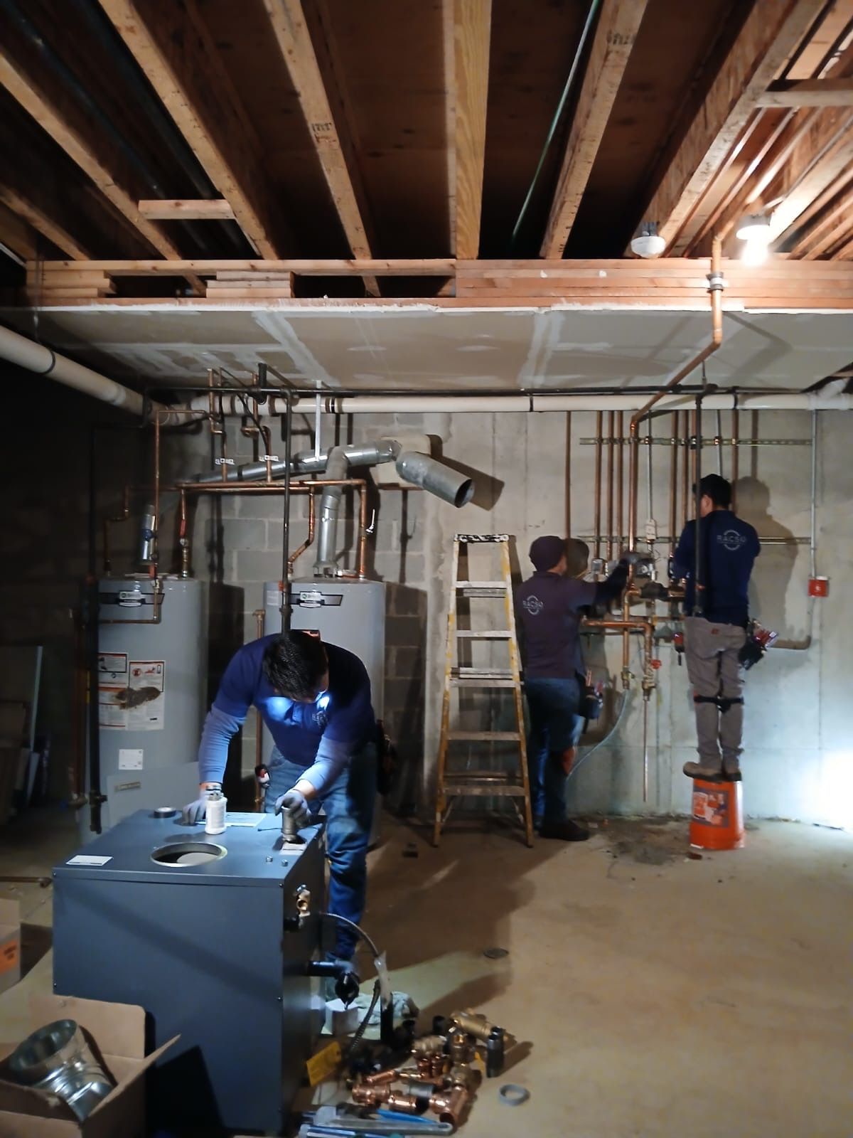 A group of men are working on a heating system in a basement