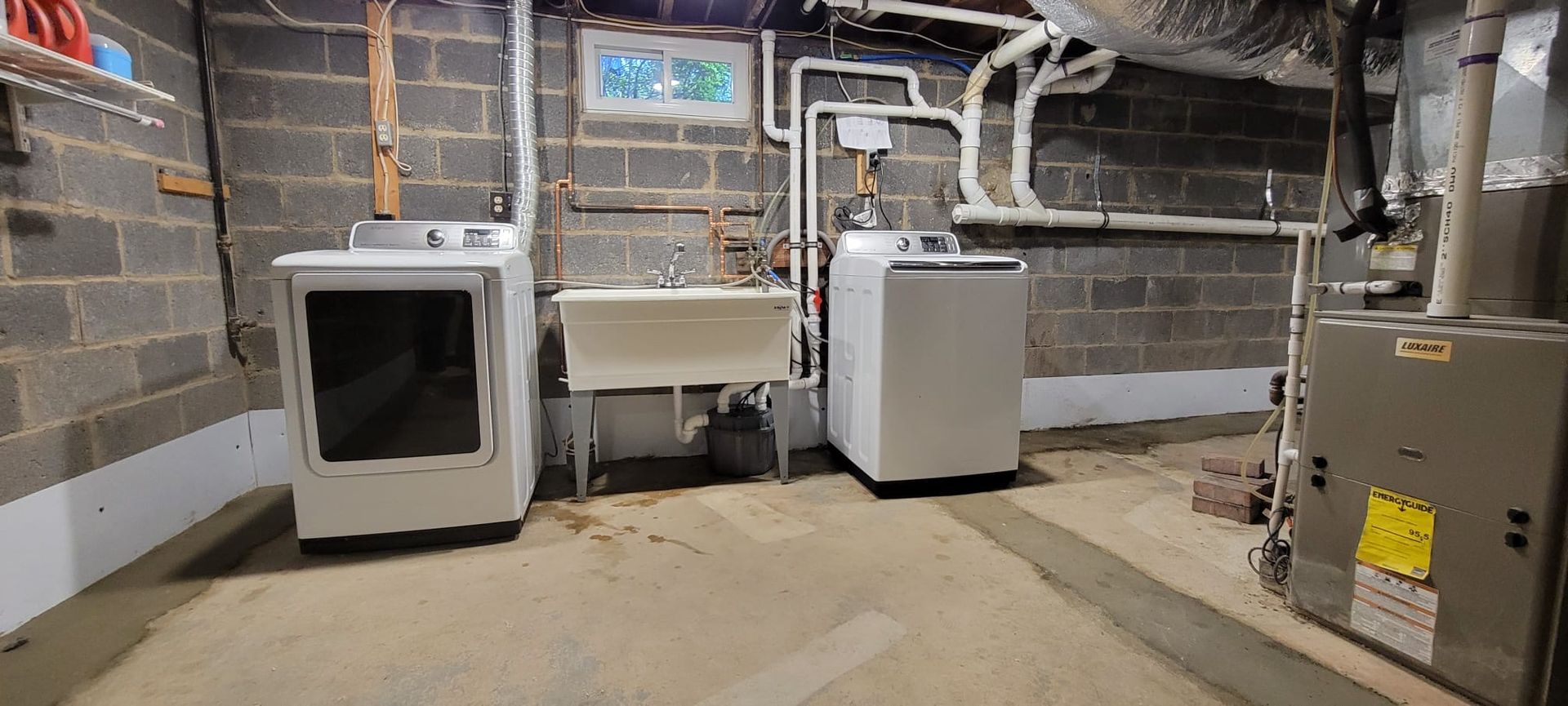 A laundry room with a washer, dryer,  sink, and a heating equipment