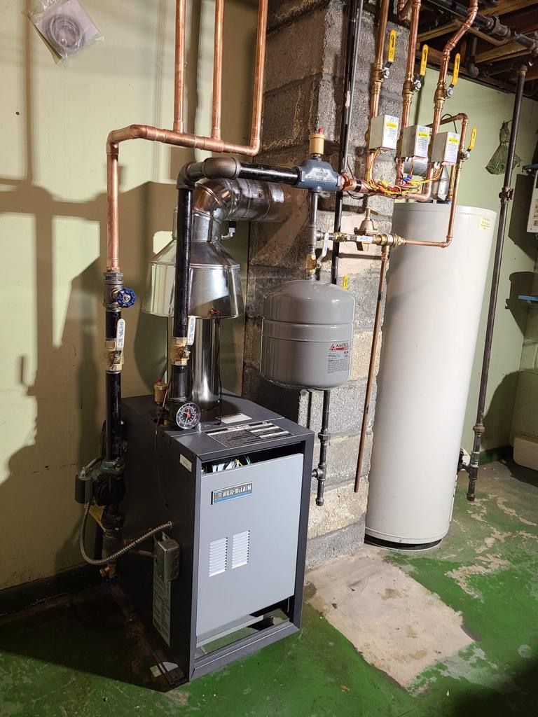 A gas boiler in a basement next to a water heater
