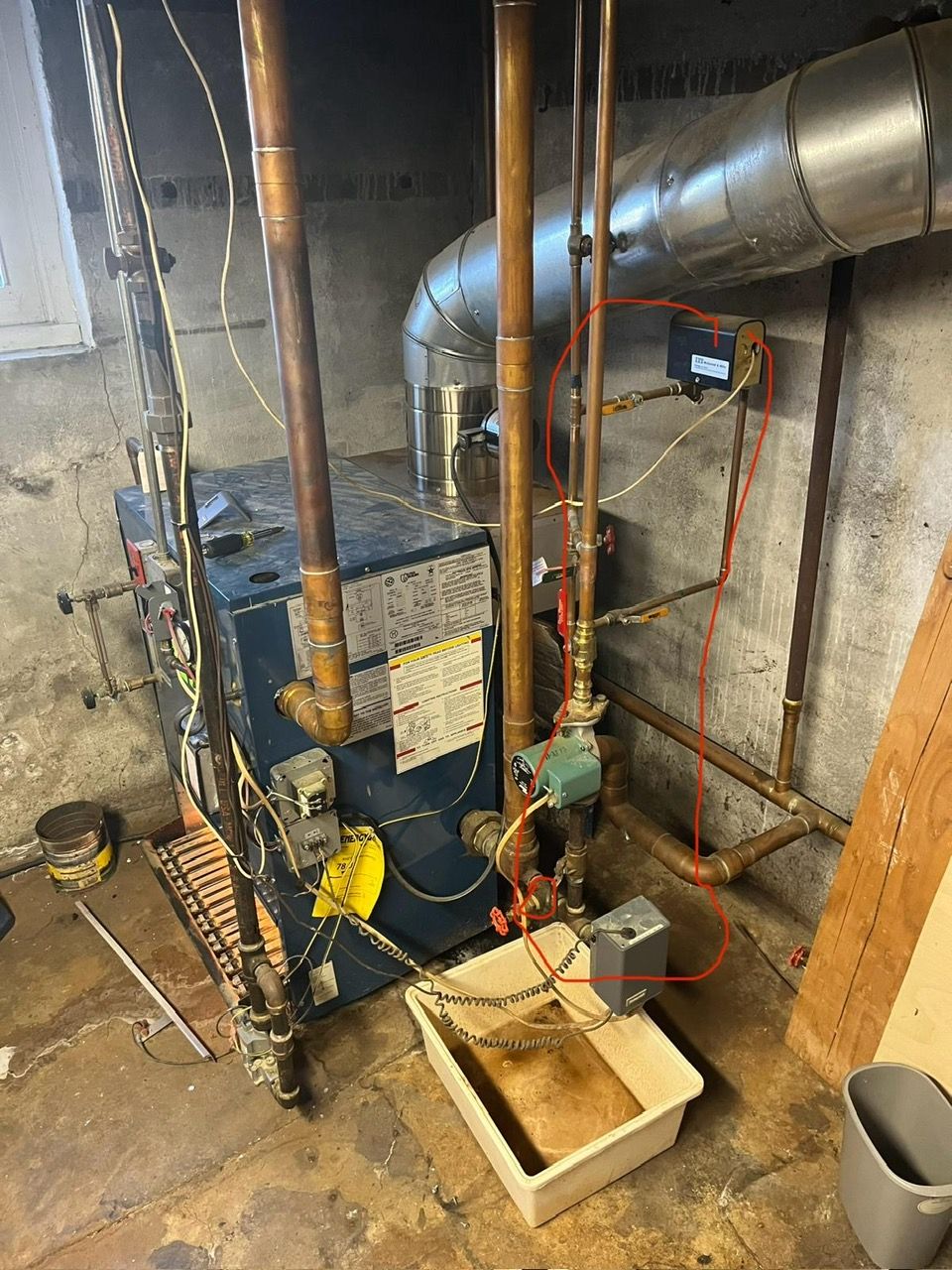 A blue boiler in a basement with several pipes