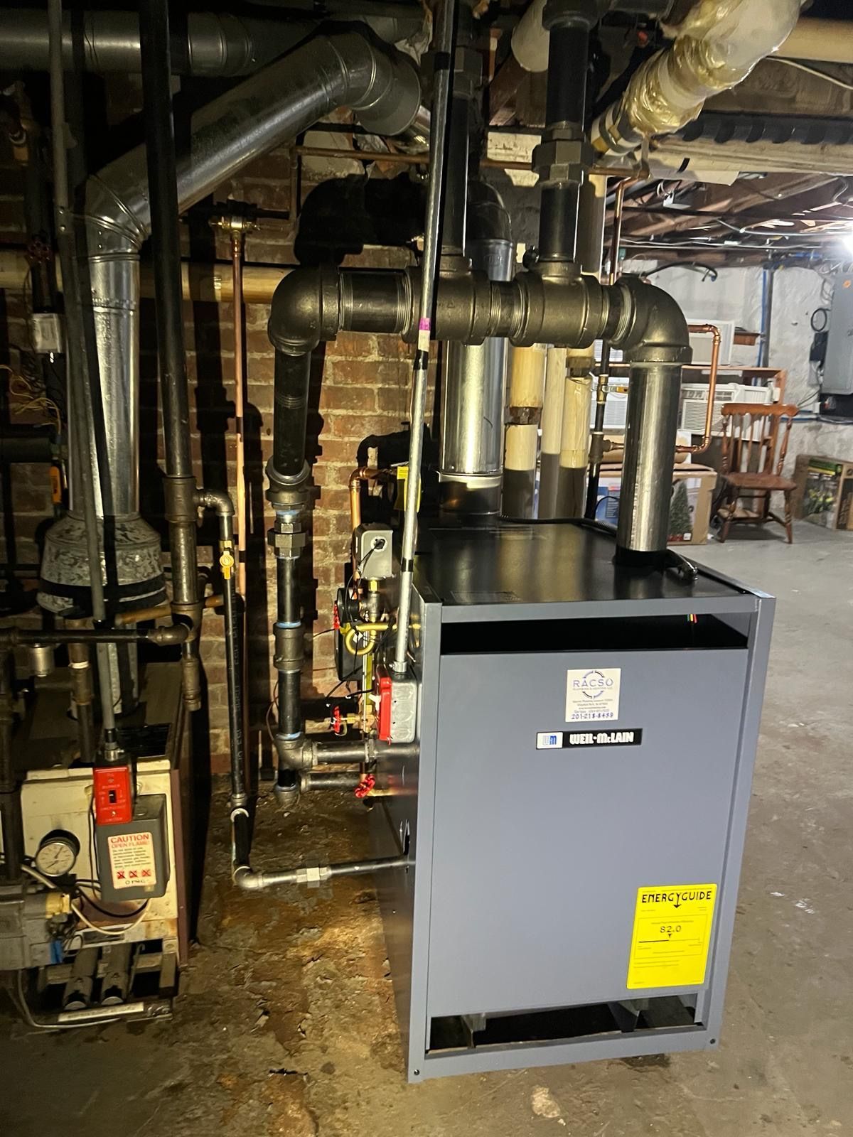 A boiler in a basement next to a brick wall