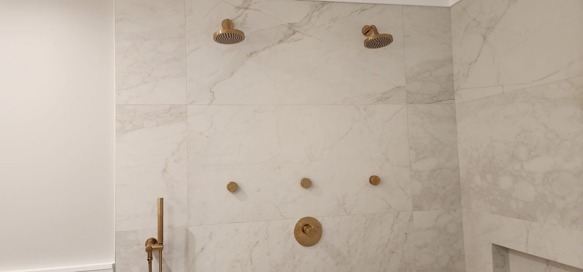 A bathroom with marble tiles and two shower heads