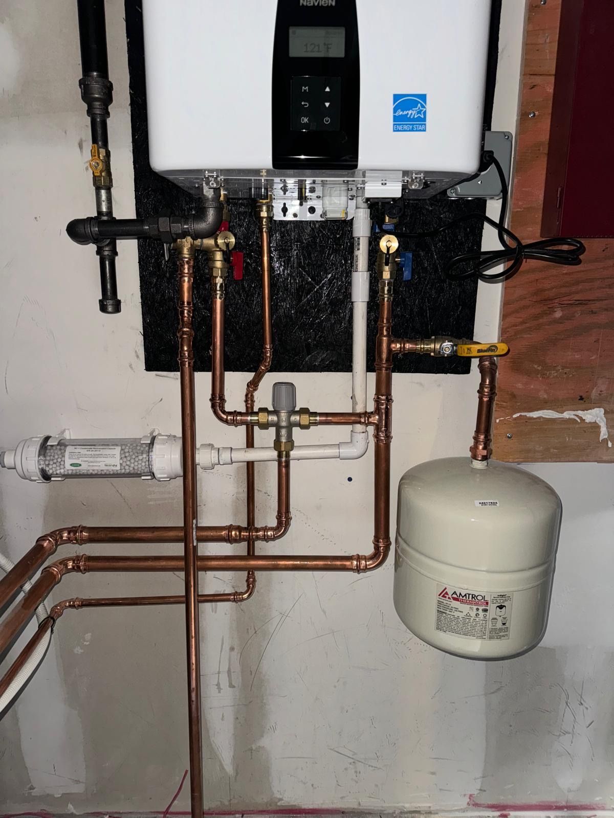A water heater is mounted to a wall with copper pipes