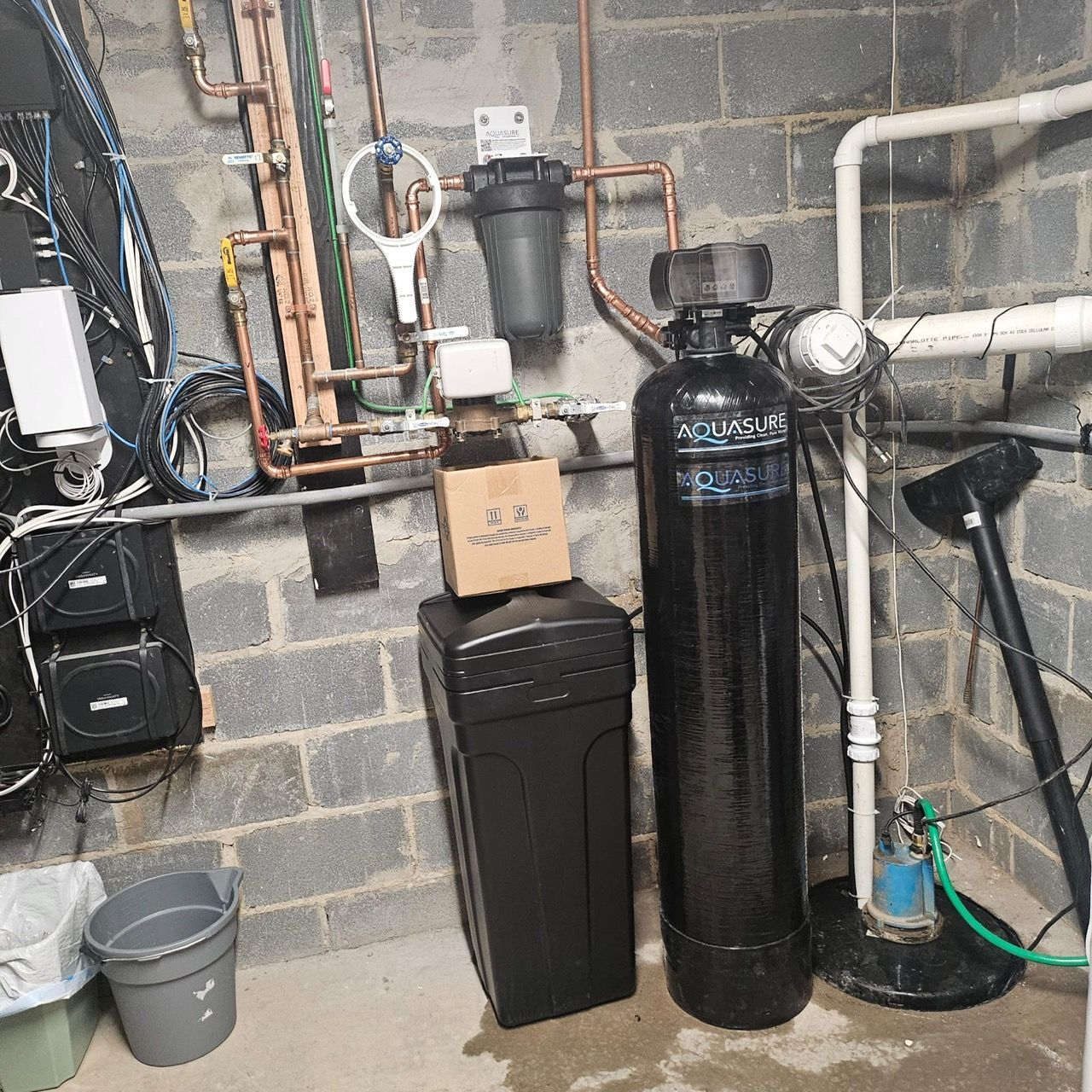 A black water softener is sitting in a basement