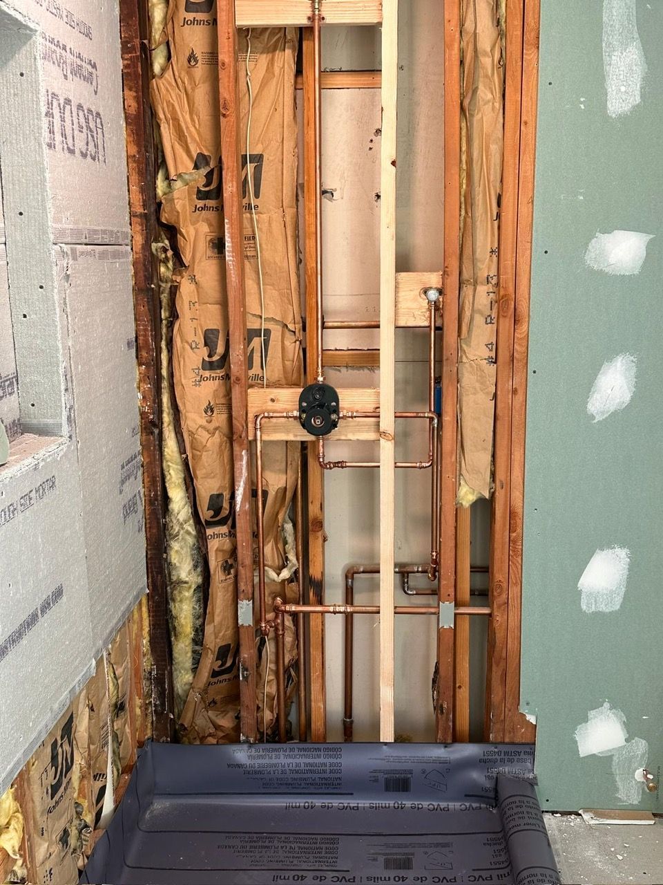 A bathroom under construction with a shower stall in the middle of the room