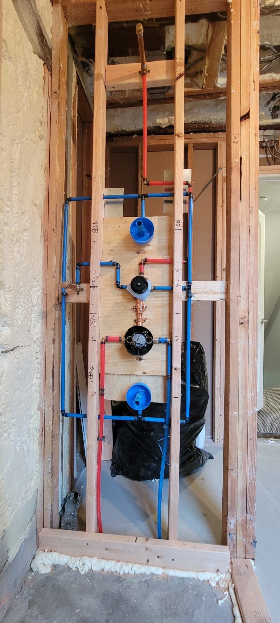 A bathroom under construction with a lot of pipes on the wall