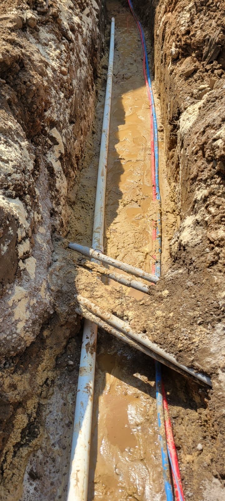 A pipe is being installed in a trench in the dirt