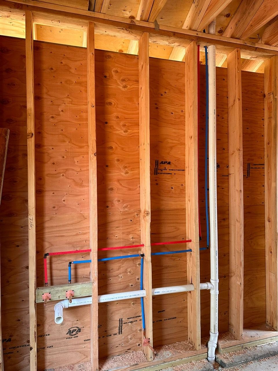 A wooden wall with plumbing pipes 