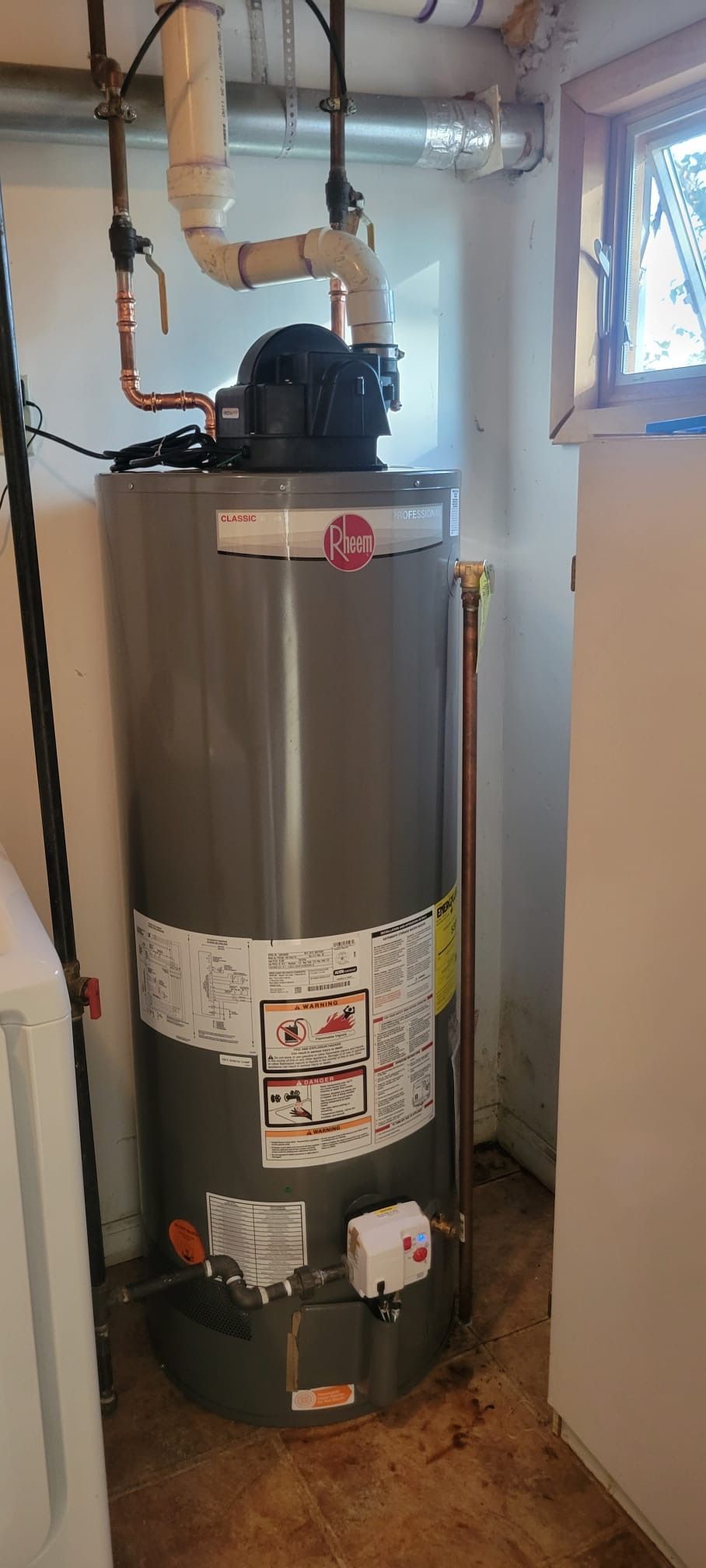 A water heater is sitting in a room next to a window