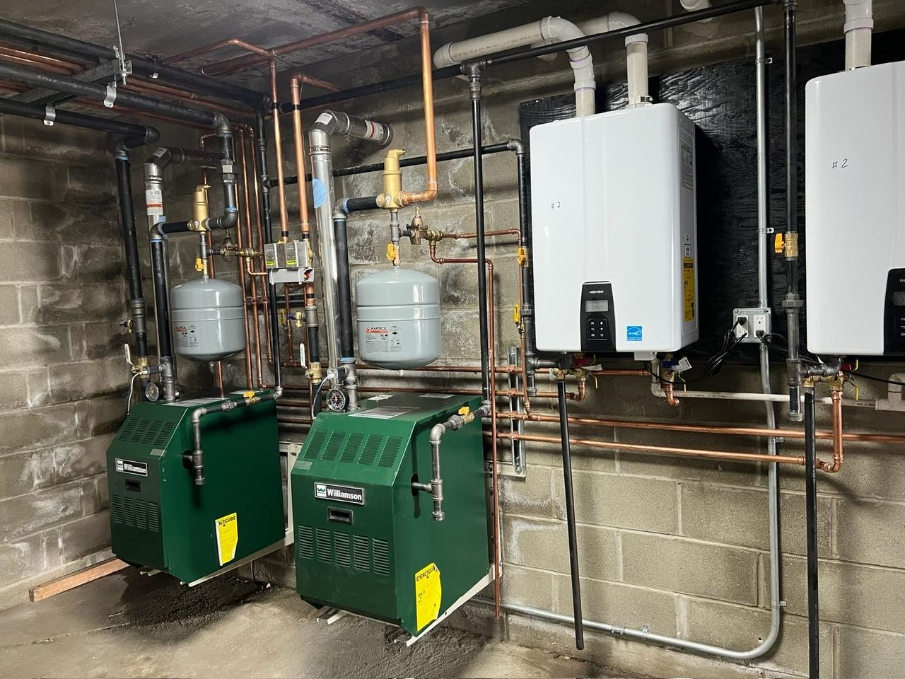Three boilers are placed next to each other in a basement