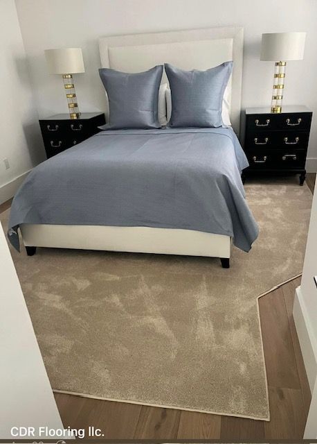 A bedroom with a bed , nightstands , lamps and a rug.