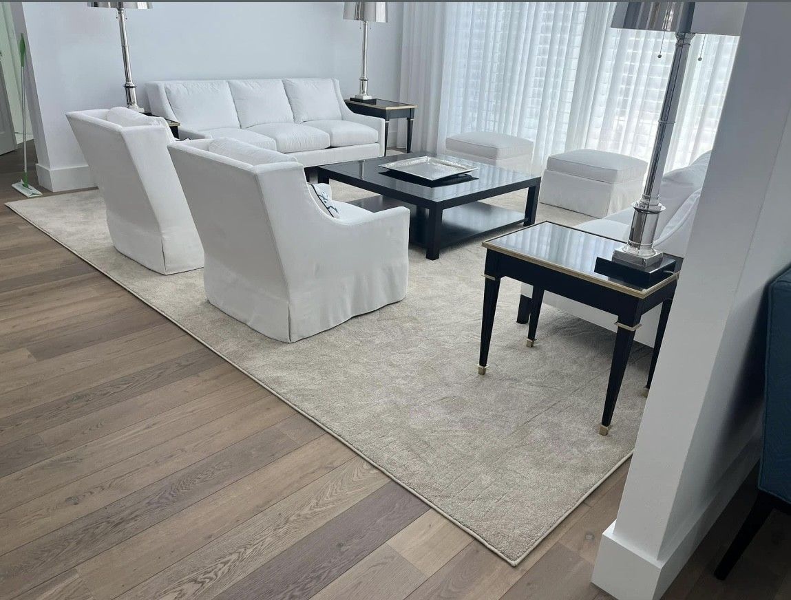 A living room with a couch , chairs , coffee table and rug.