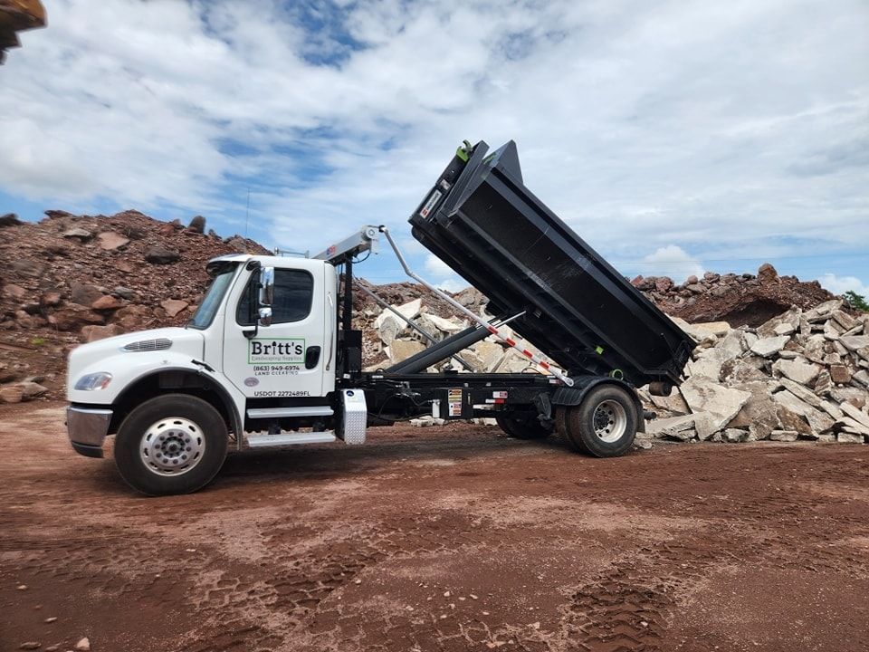 A dump truck is parked in front of a pile of rocks.