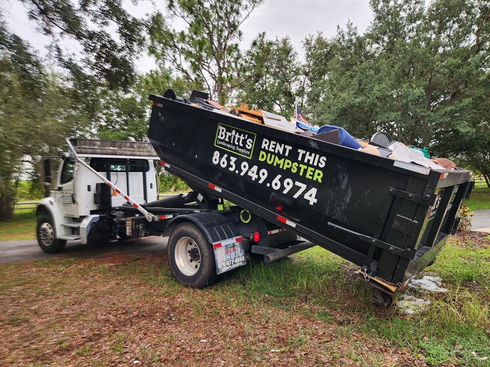 A dumpster is being pulled by a dump truck.