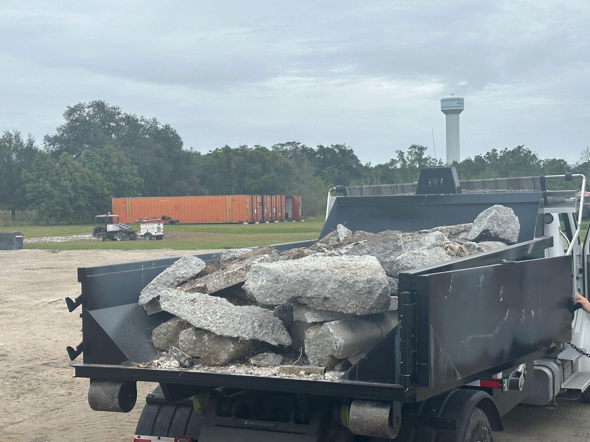 A dump truck is filled with rocks in a parking lot.
