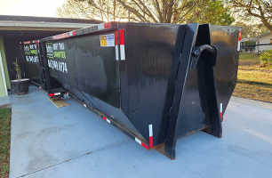 A dumpster is sitting in the driveway of a house.