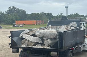 A dump truck filled with rocks is parked in a parking lot.