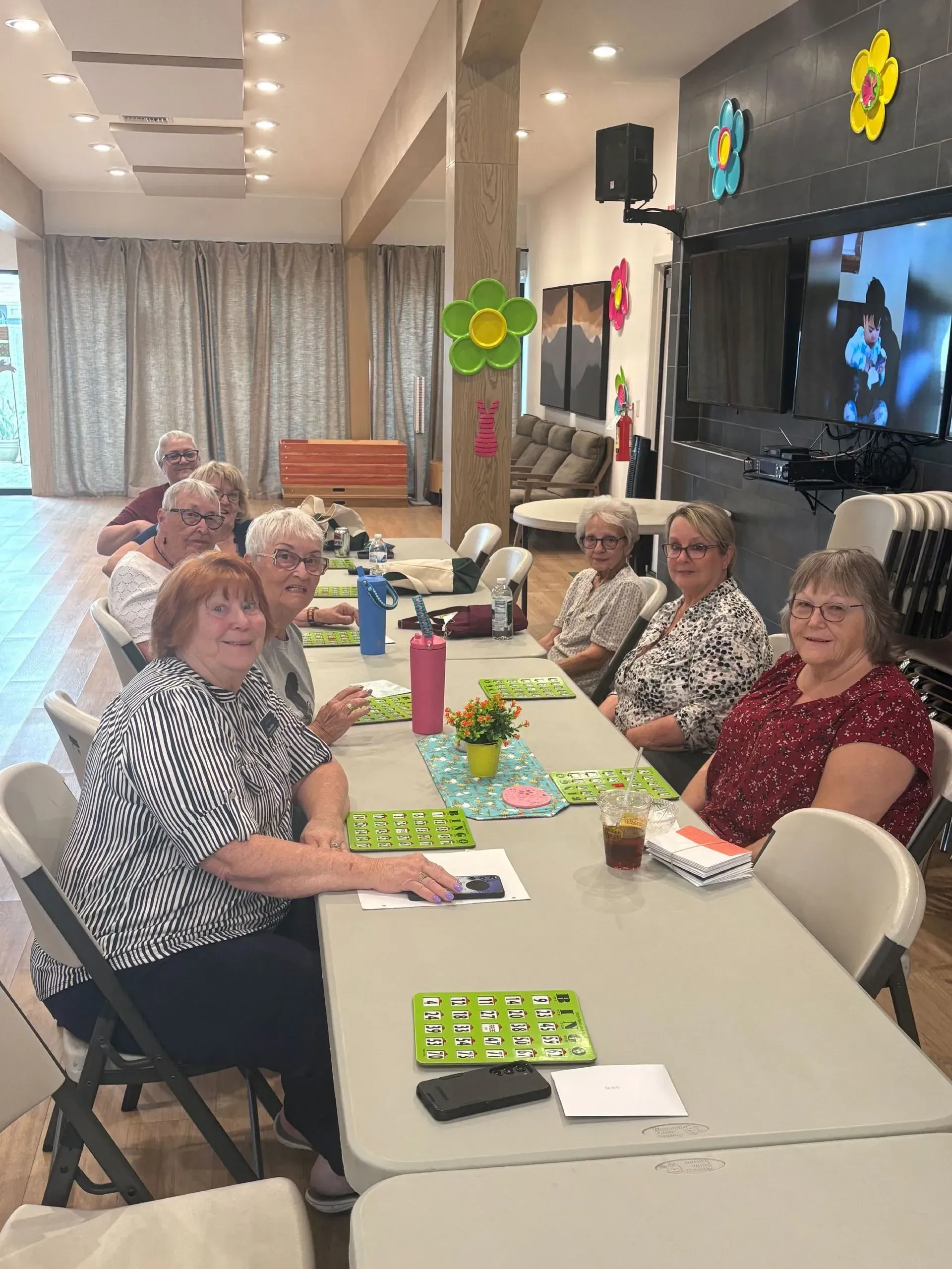 People seated at a long table playing a game in a bright community room