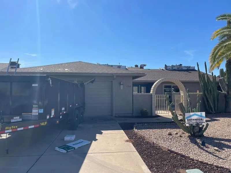 Single-story house with a gray garage, front walkway, and desert landscaping under a bright blue sky