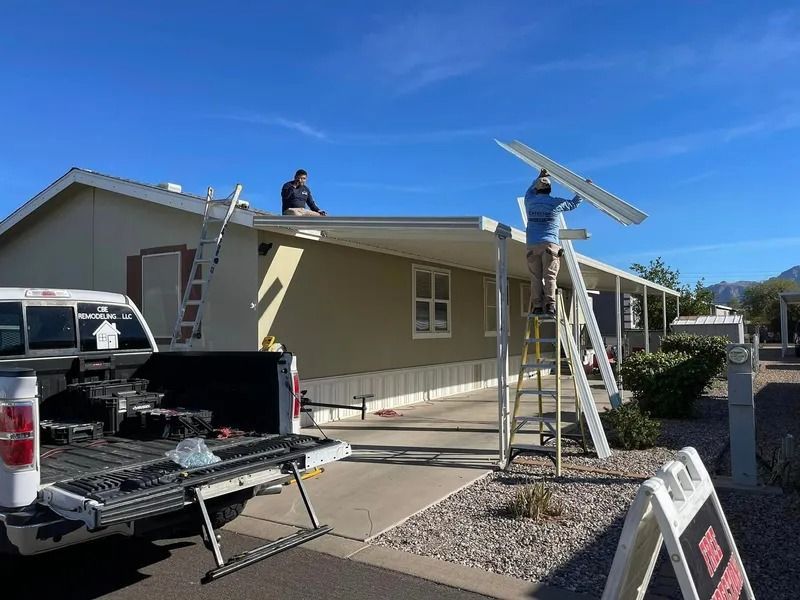 Workers installing solar panels on a house roof, with ladders and a truck in the driveway.