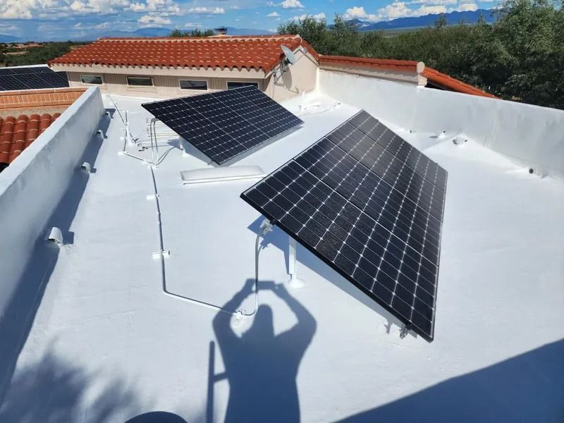 Solar panels mounted on a white rooftop, with a person’s shadow visible in the foreground.