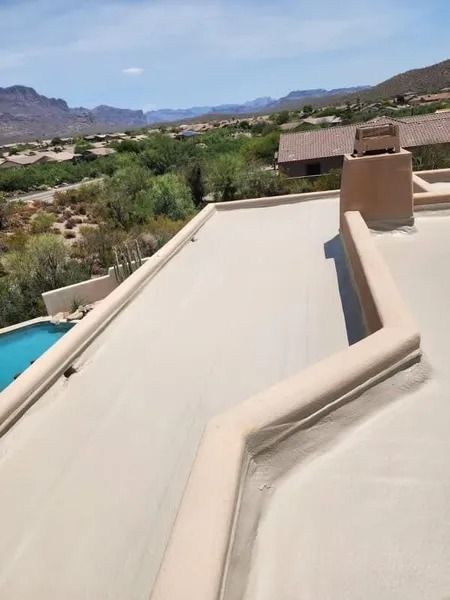 Rooftop terrace with beige walls overlooking a desert valley and mountains under a clear sky