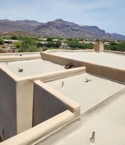 Desert hillside homes with flat tan roofs and mountains in the background under a clear sky